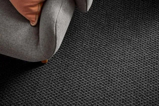 A Chair is Sitting on a Black Carpet Next to a Couch — Aussie Carpets & Vinyl In Beerwah, QLD