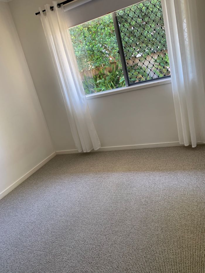 An Empty Room With a Carpeted Floor and a Window — Aussie Carpets & Vinyl In Sunshine Coast, QLD