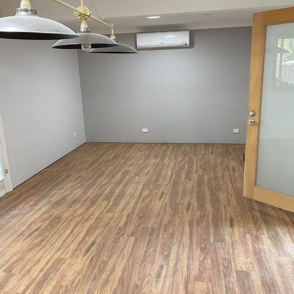 An Empty Room With Wooden Floors and a Door — Aussie Carpets & Vinyl In Maleny, QLD