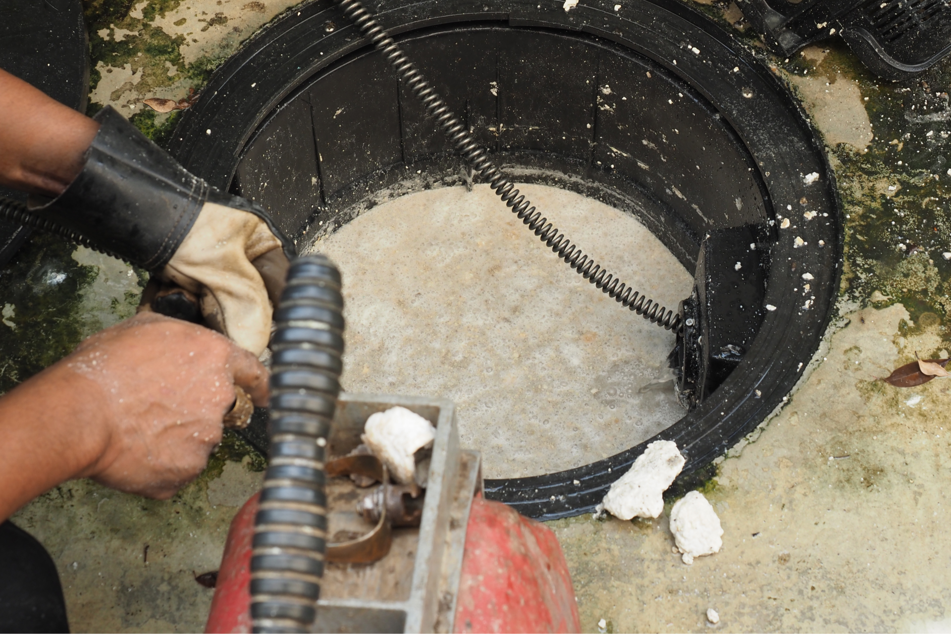 Worker using a hose to pump water from a manhole or underground tank