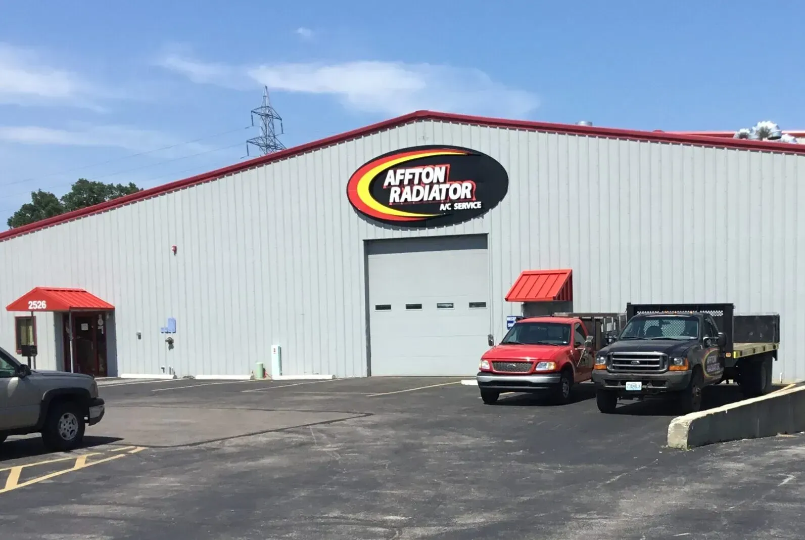 Auto repair shop building with parked trucks under a clear sky