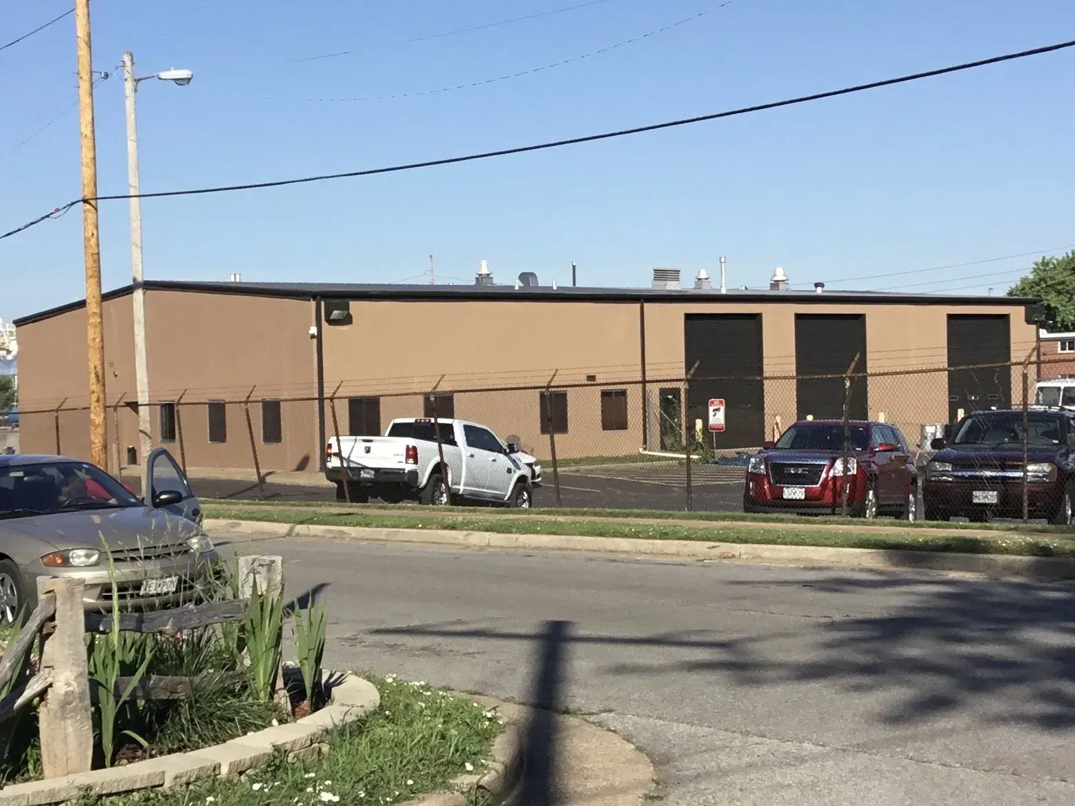 Low tan industrial building with parked vehicles under a clear sky