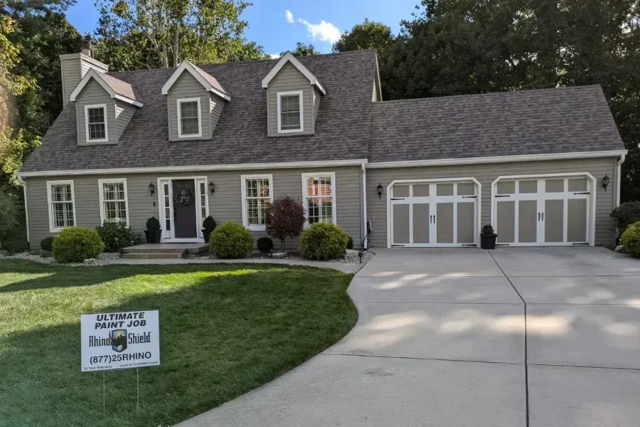Suburban house with two-car garage and a real estate sign on the front lawn