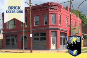 Red brick corner building with storefront windows and a Brick Exteriors sign on the left.