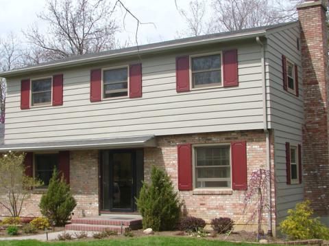 Two-story brick and siding house with red shutters and a small front porch