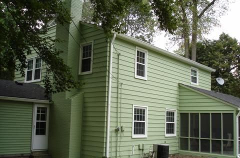 Light green two-story house with white trim and screened porch under trees