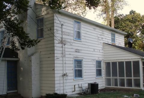 White two-story house with blue-trimmed windows and a screened porch, seen from the side.