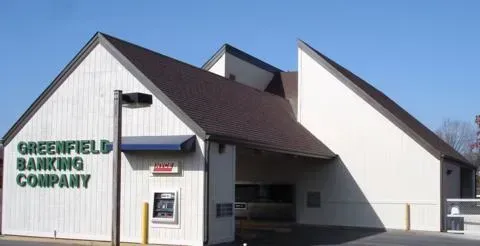Greenfield Banking Company building with white walls and a dark roof under a clear blue sky