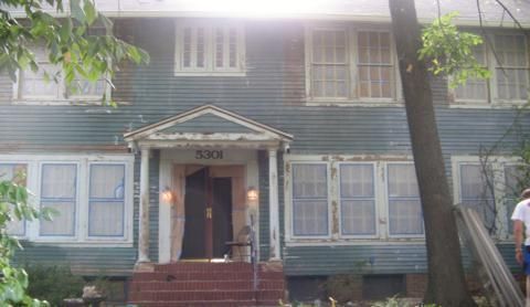 Blue two-story house with a small front porch and steps, framed by trees in front
