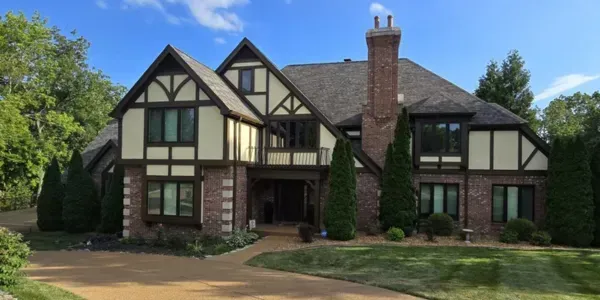 Tudor-style brick and timber house with a central chimney and manicured front lawn