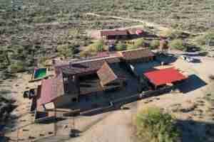 Aerial view of a desert resort with red-roofed buildings and a central courtyard pool