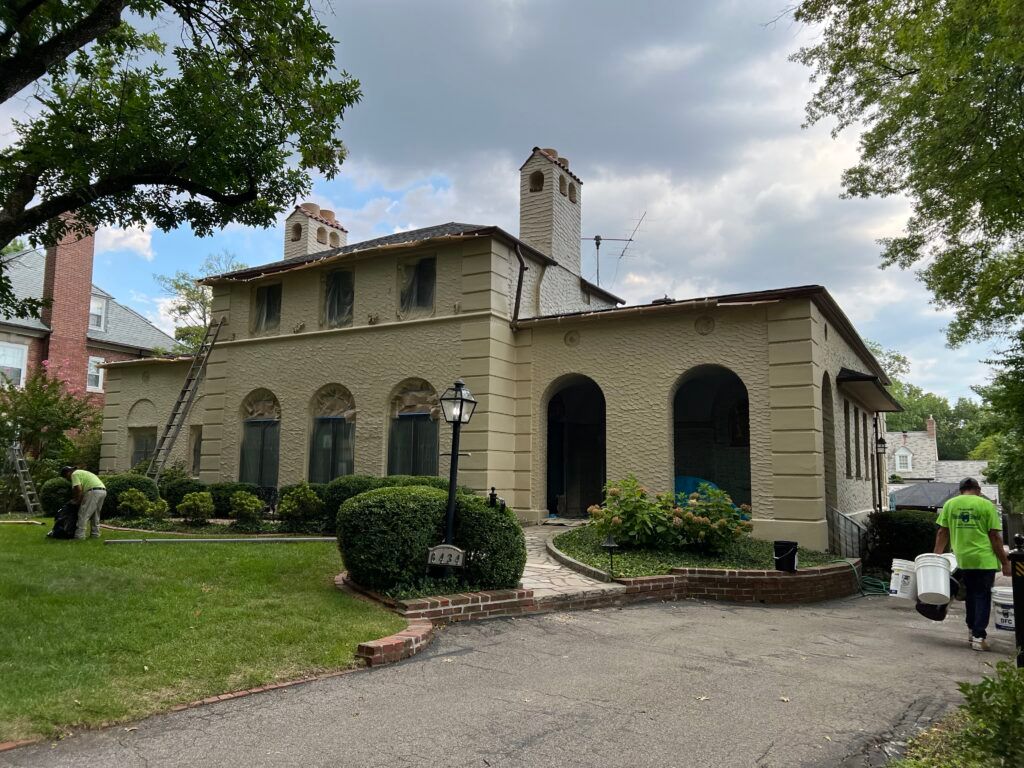 Historic beige stone building with arched windows, a driveway, and a person walking near the entrance.