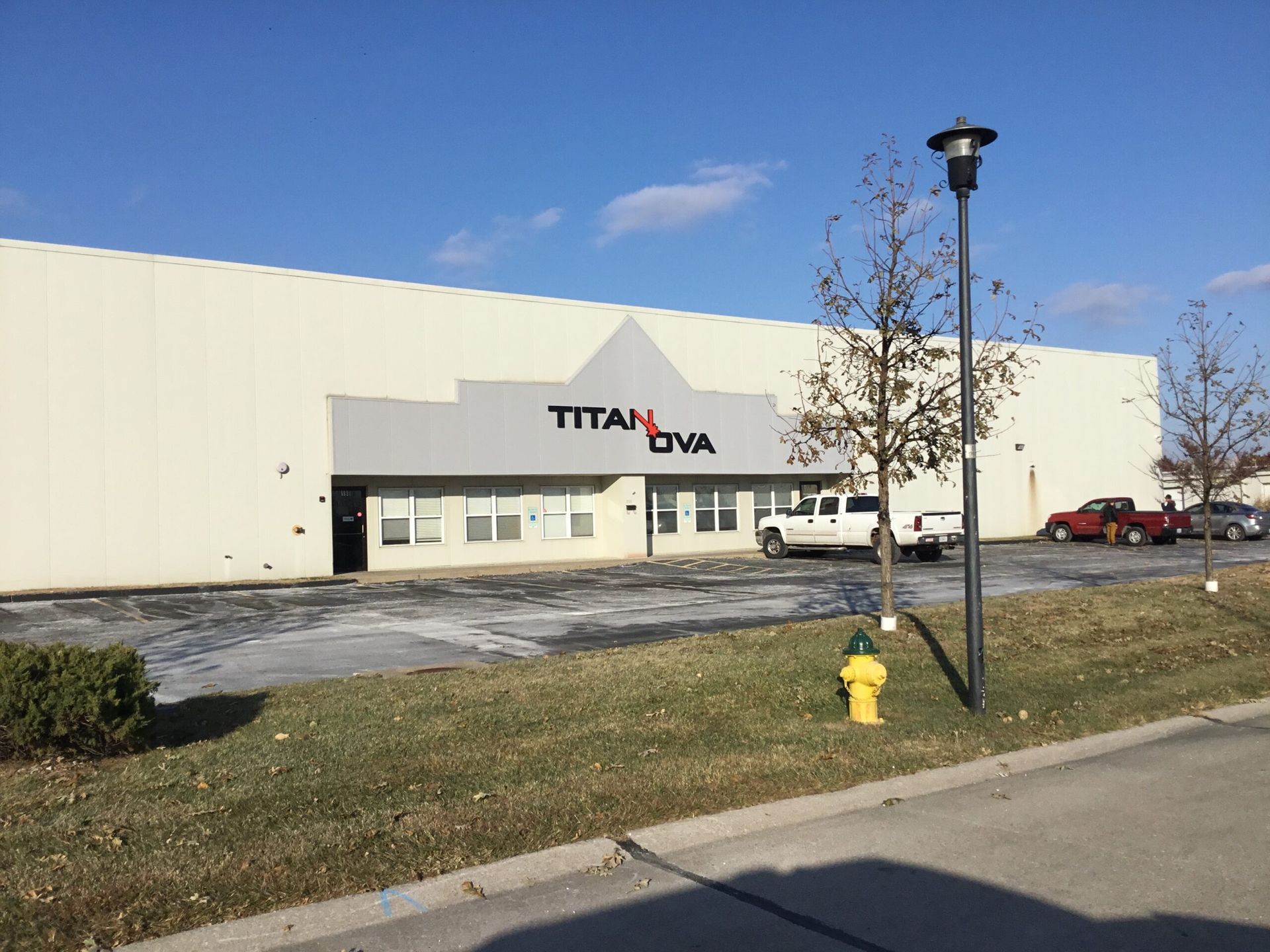 Titan USA warehouse building with parking lot, trees, and a yellow fire hydrant under a blue sky