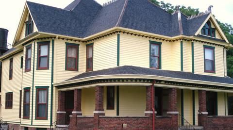 Victorian-style yellow house with brown trim and a covered porch