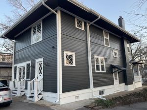 Dark gray two-story house with white trim and porch on a residential street