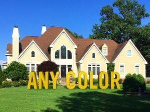 Suburban house with bright yellow “ANY-COLOR” lettering on the lawn