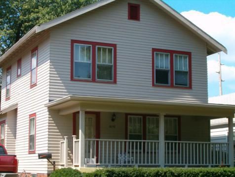Two-story white house with red-trimmed windows and a covered front porch