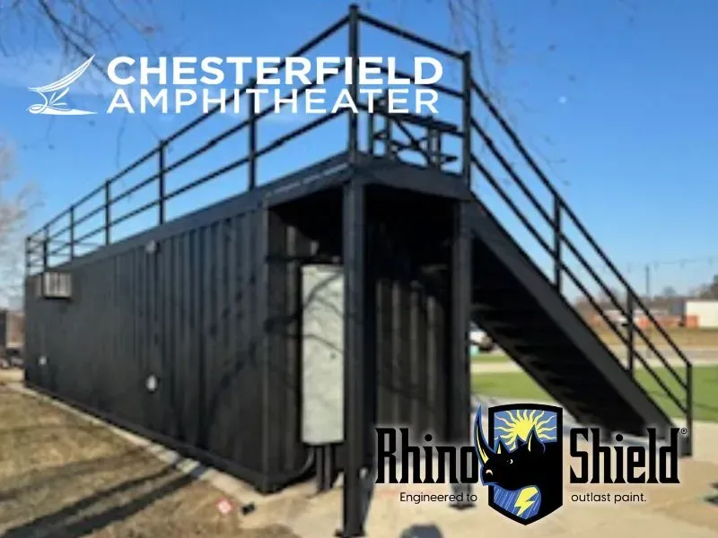 Black shipping-container structure with stairs and railings at Chesterfield Amphitheater, Rhino Shield logo visible