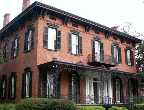 Two-story red brick house with black shutters and a covered front porch