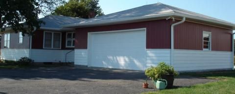 Single-story red and white house with a two-car garage and small potted plant in front