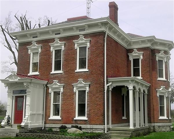 Red brick Victorian house with white trim, tall windows, and a red front door.