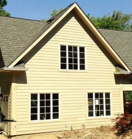 Cream-colored house exterior with steep gable roof and white-trimmed windows.