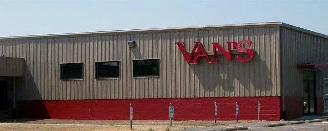Vans store exterior with red logo on a gray building and red lower facade