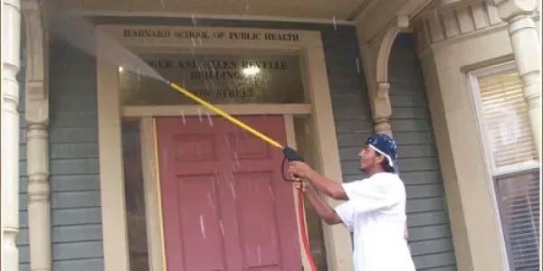 Man measuring the height of a pink front door with a long yellow pole on a porch
