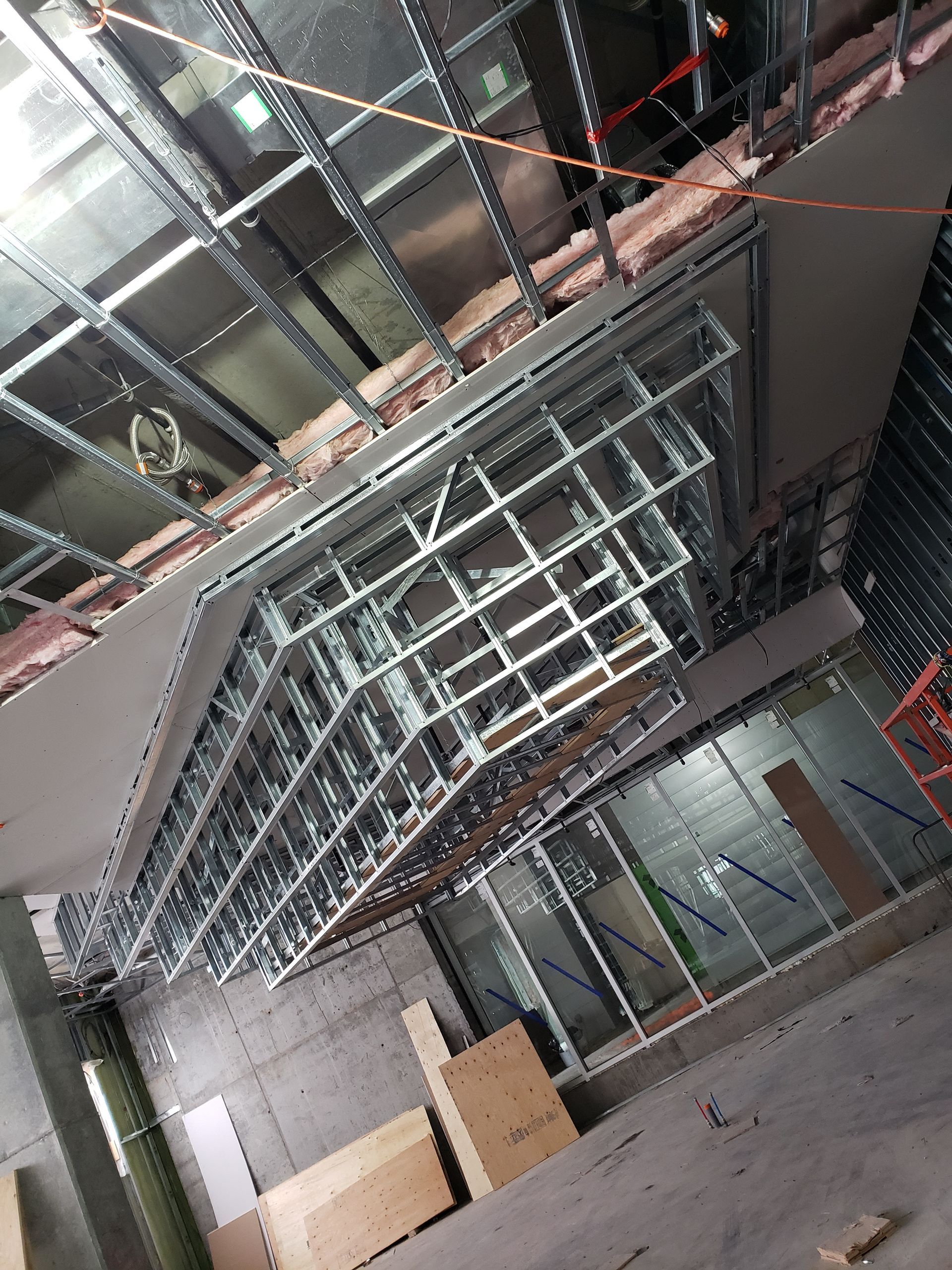 Intérieur de chantier, structure métallique pour le plafond et les murs ; pose de plaques de plâtre en cours.
