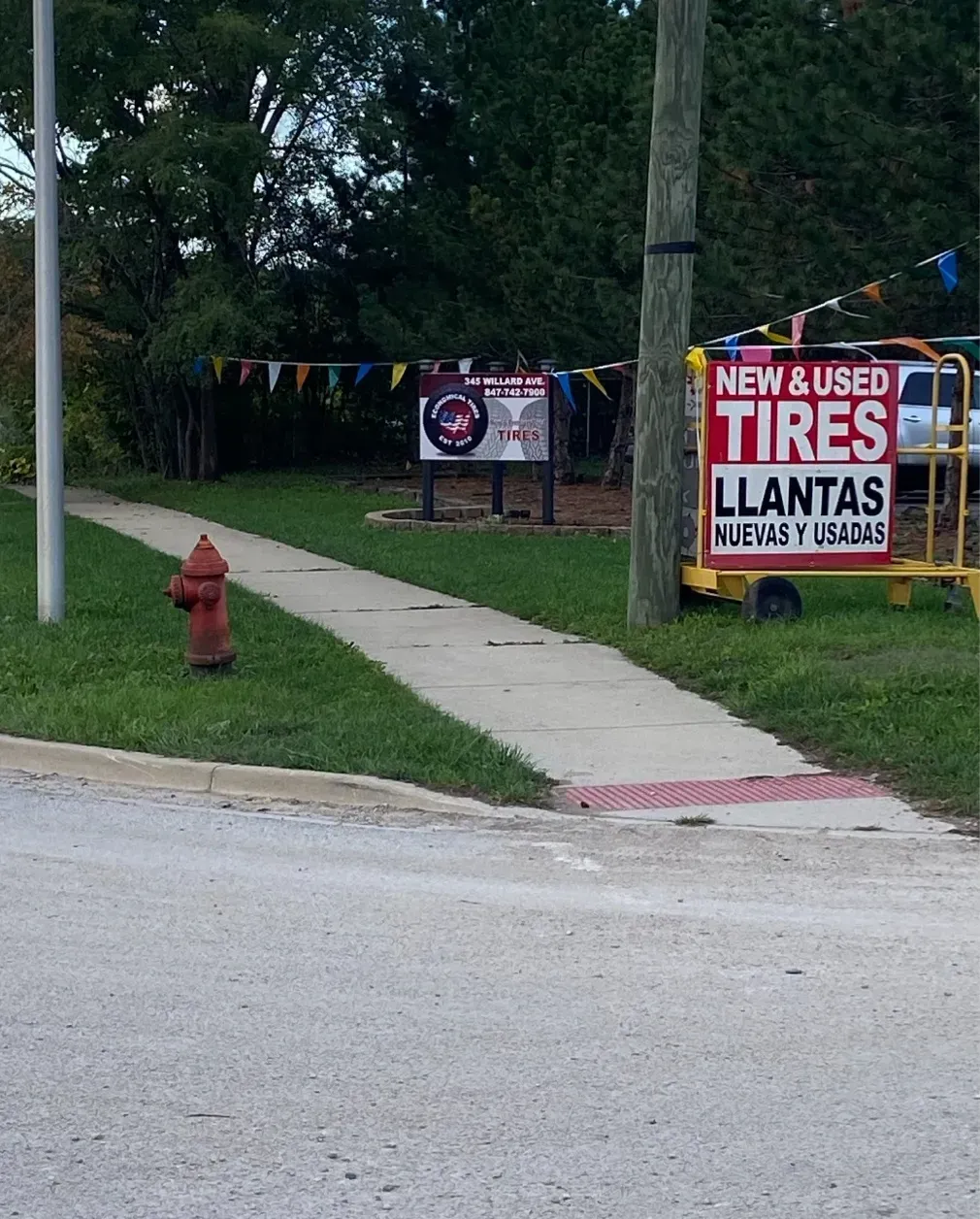 Sidewalk leading to a tire shop with a sign advertising