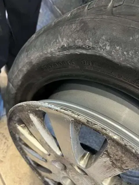 Flat car tire with separated rubber and damaged rim.