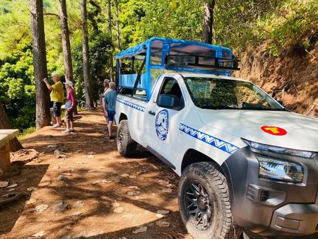 White off-road rescue truck on a forest trail beside hikers and tall trees