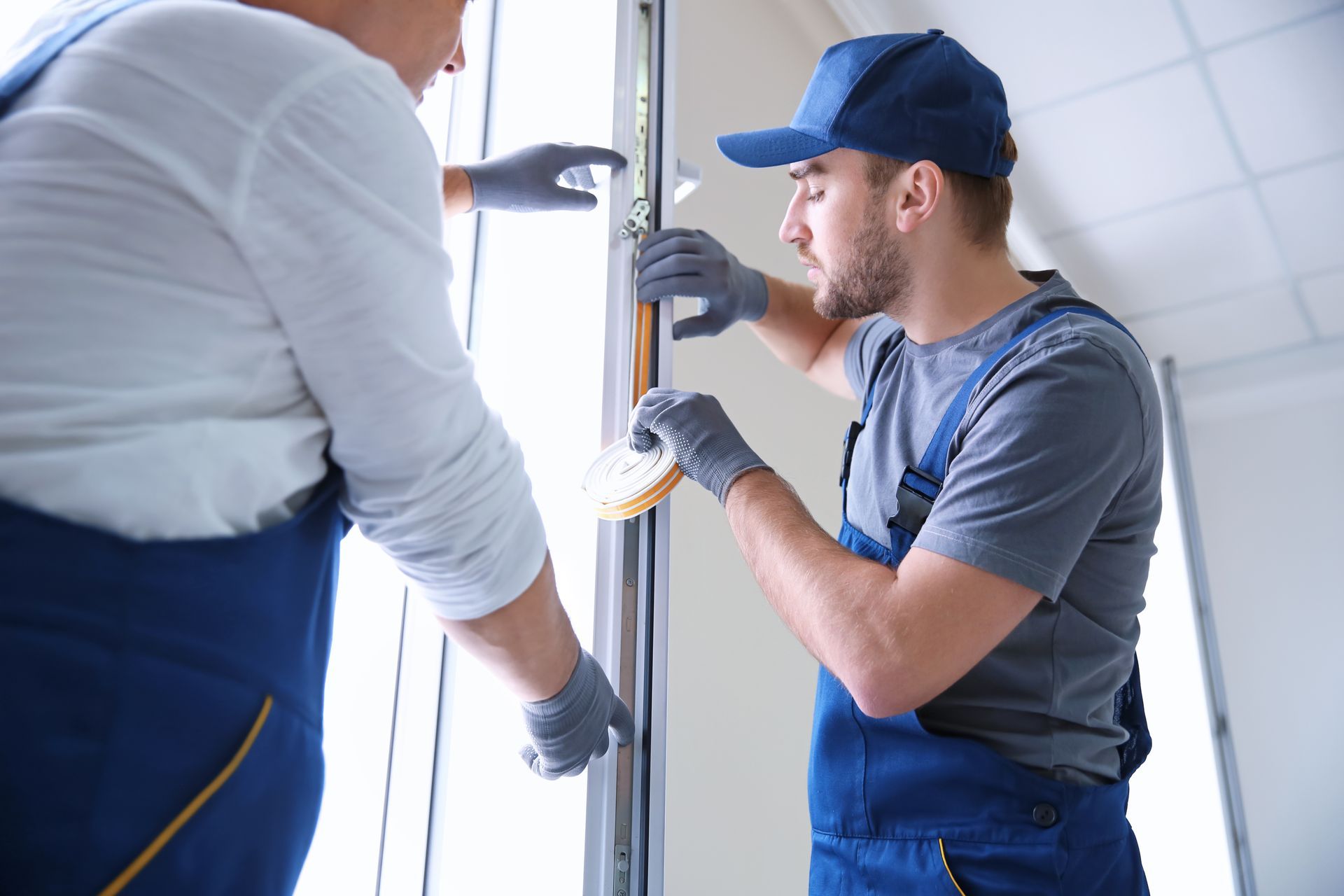 Experienced construction worker instructing a trainee on installing a window in a house.