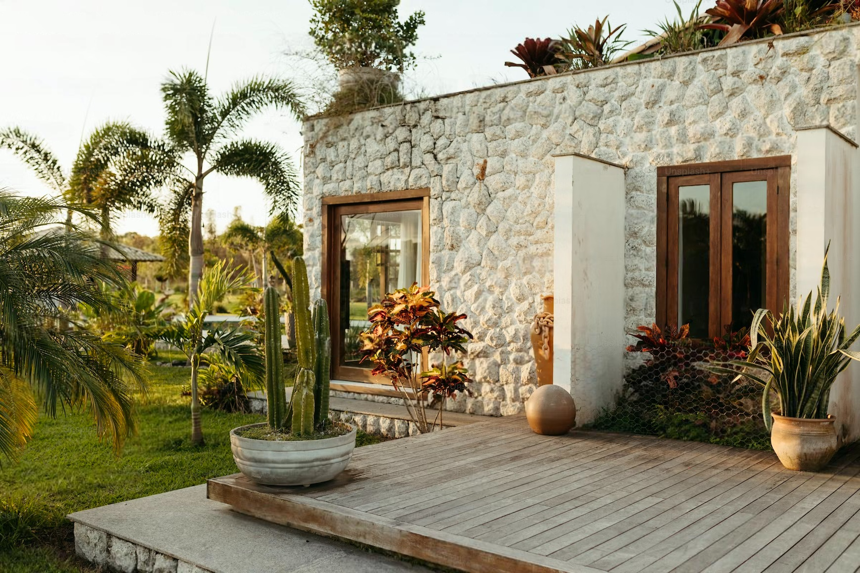 a white stone house with a wooden deck in front of it