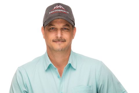 Portrait of a man in a gray cap and light blue shirt, standing against a white background
