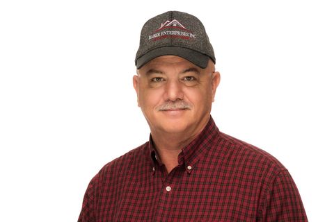 Man wearing a black cap and red plaid shirt, smiling against a white background