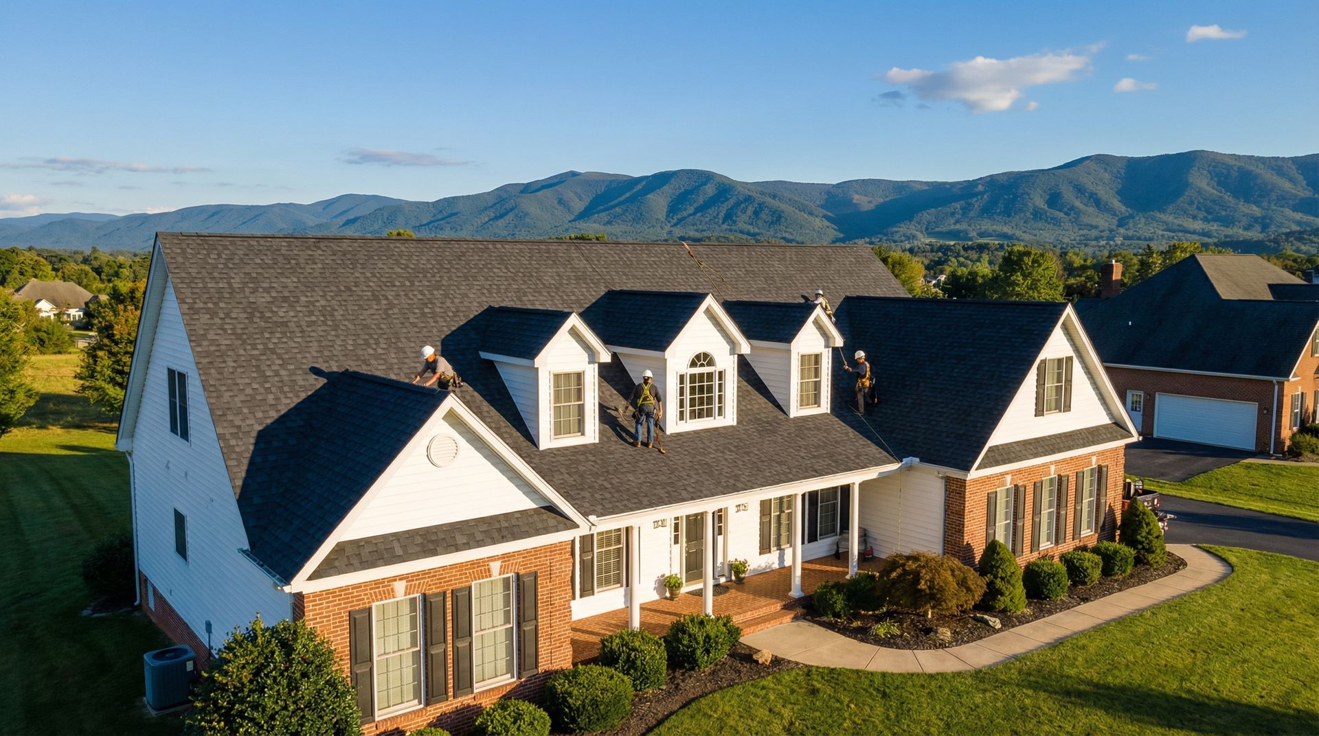 Large white-and-brick suburban house with dark roof, mountain backdrop, and landscaped lawn