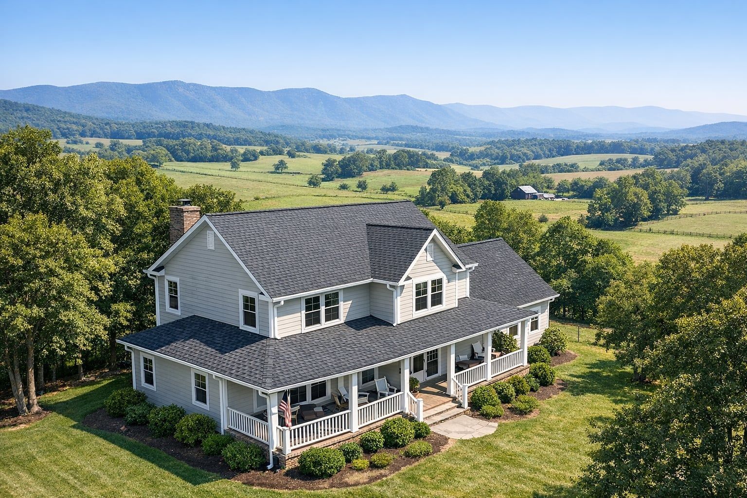 Aerial view of a Valley home with a gray shingle roof and white gutters, mountains beyond