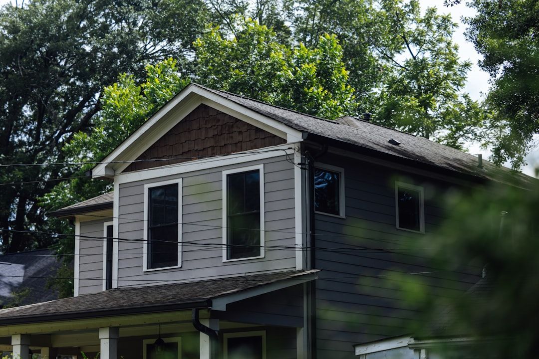 Two-storey grey American home with an asphalt shingle roof among mature trees