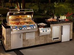 Outdoor kitchen with stainless steel grill and sink on a stone counter at night