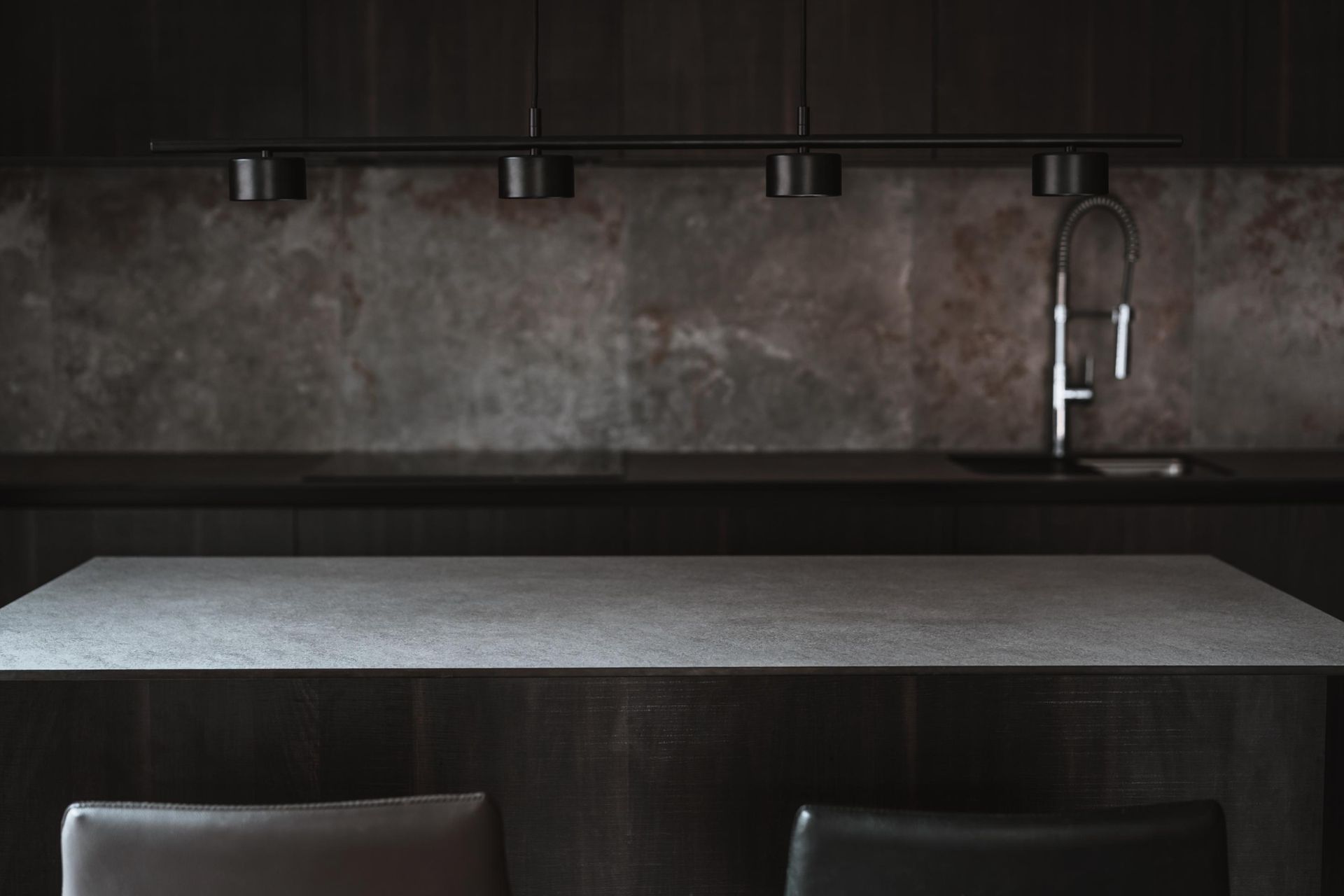 Dark modern kitchen with gray countertop and dark cabinets.