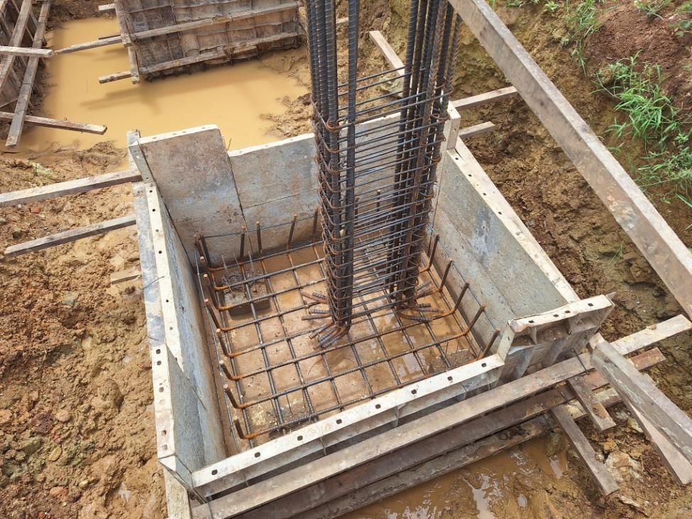 Foundation construction: Rebar framework within wooden forms, ready for concrete pour in muddy ground.