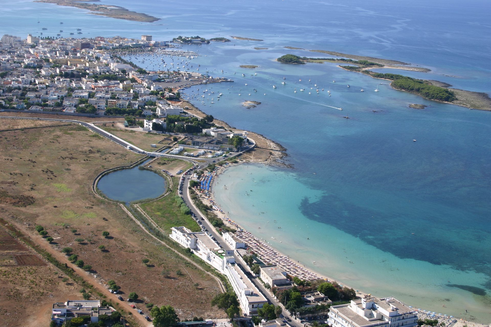 Città costiera con edifici, spiaggia e acqua azzurra.