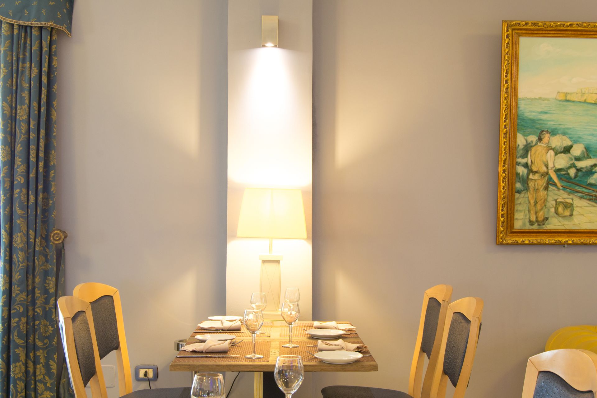 Tavolo da pranzo apparecchiato per quattro persone con una lampada da parete luminosa.