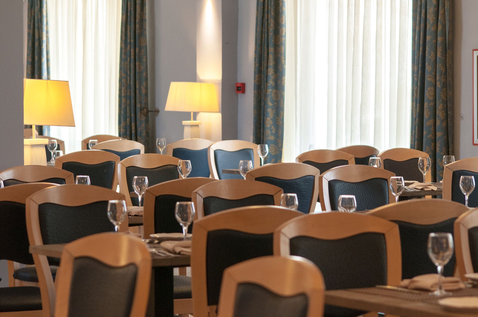 Sala da pranzo del ristorante con tavoli apparecchiati per gli ospiti, sedie in legno e lampade.