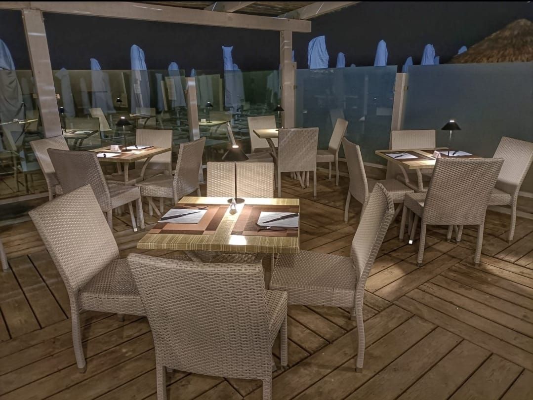 Posti a sedere all'aperto del ristorante con sedie in vimini e tavoli apparecchiati per la cena.