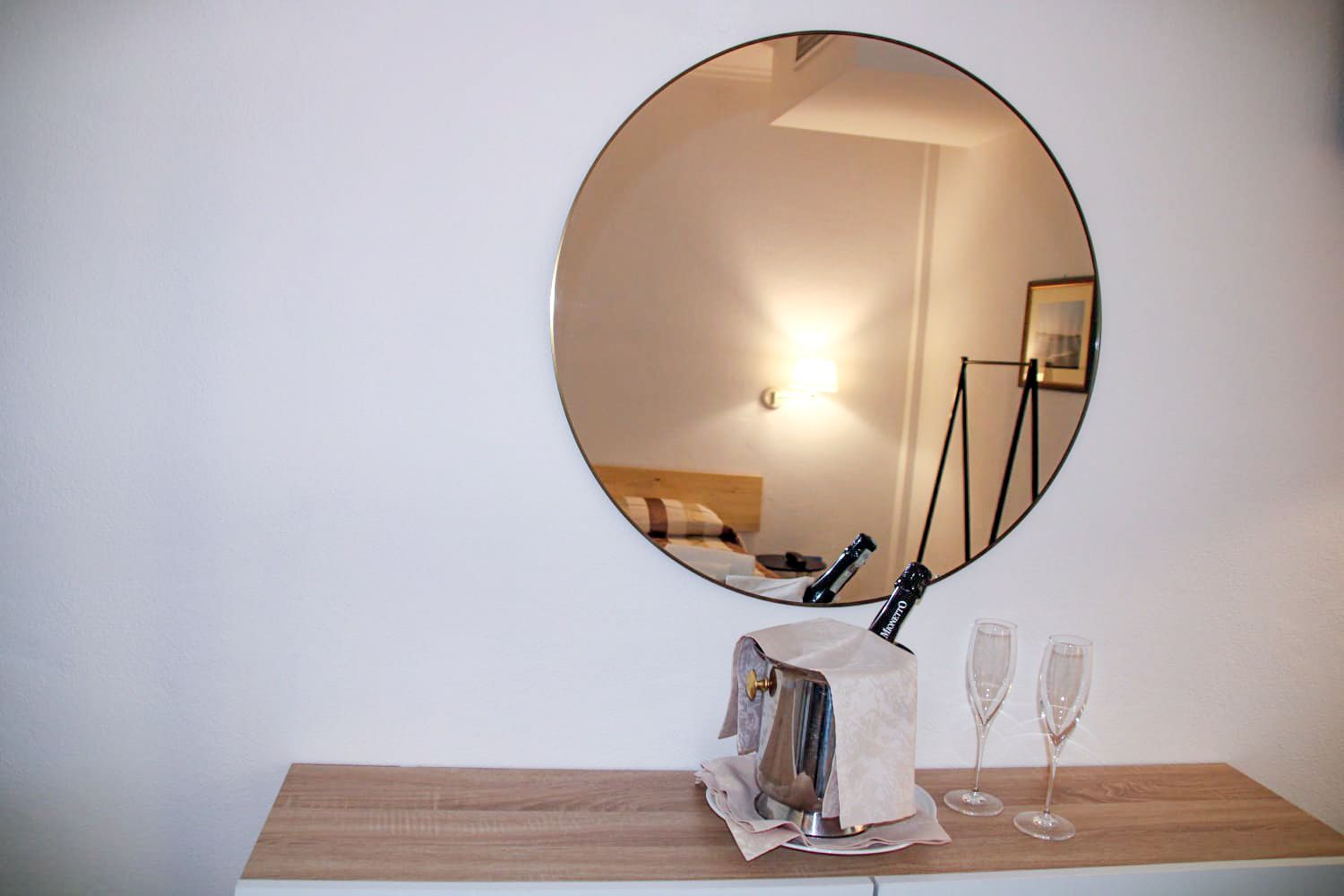 Specchio rotondo che riflette una scena di camera da letto.