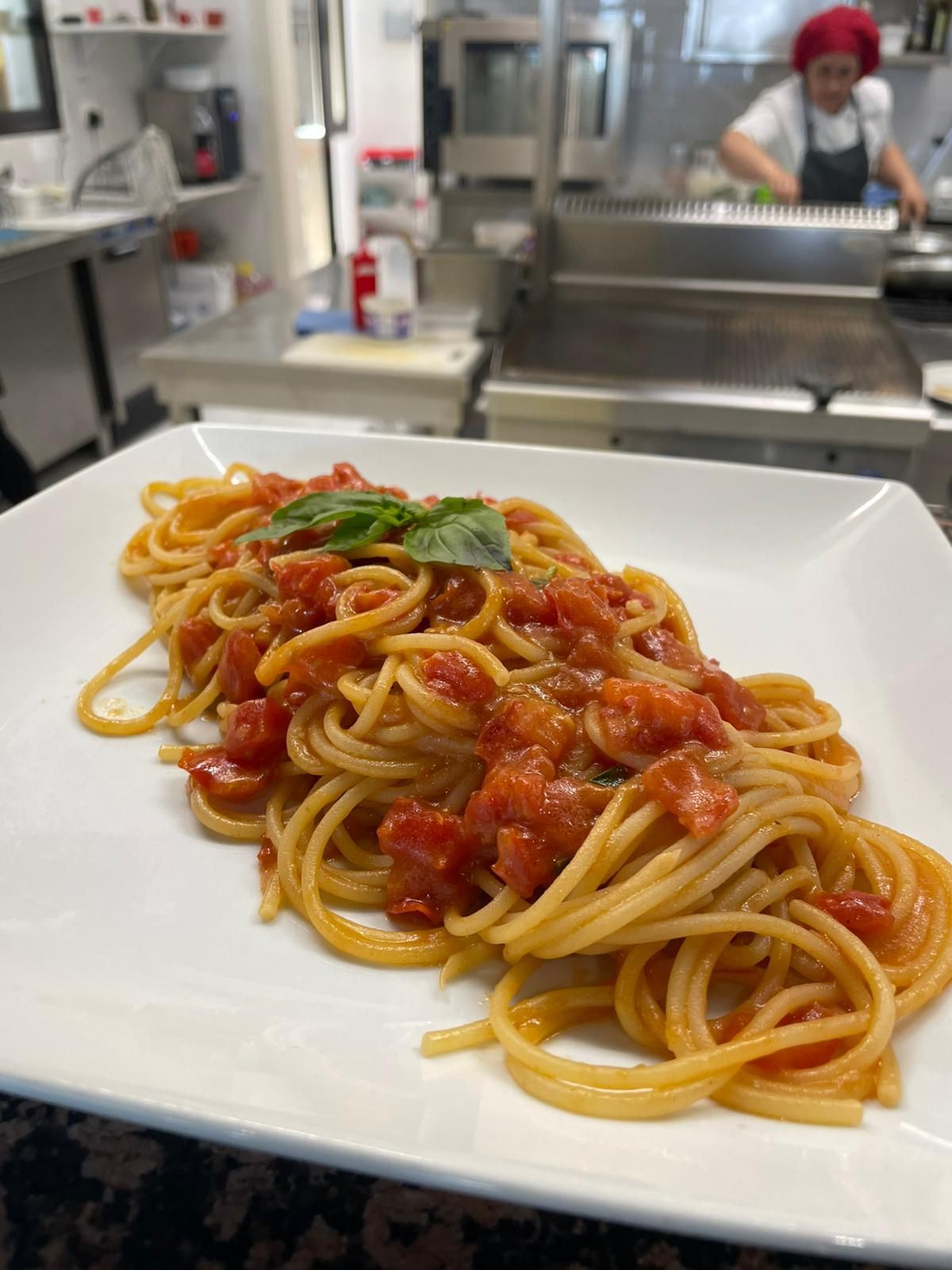 Piatto di spaghetti al sugo di pomodoro e basilico nella cucina di un ristorante.
