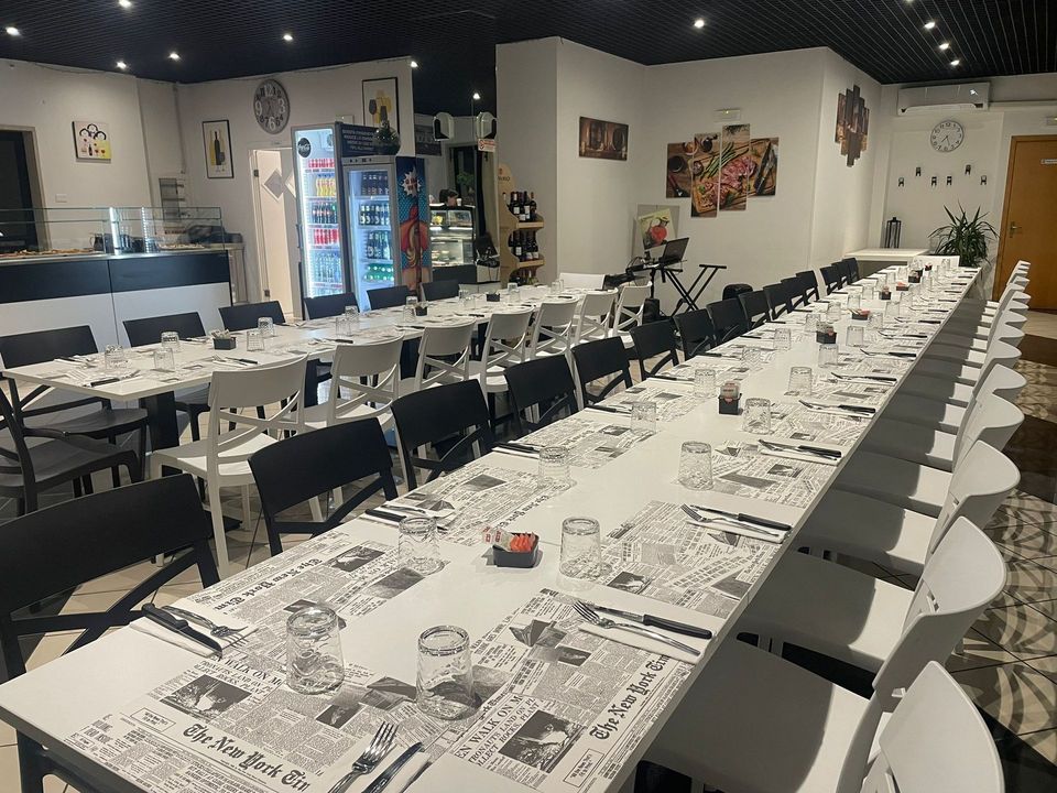 Lunghi tavoli da banchetto apparecchiati per un evento in una sala da pranzo interna decorata.