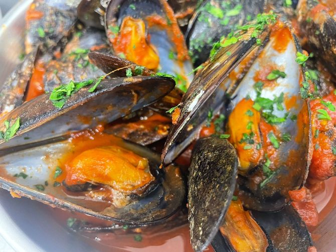 Cozze al vapore con erbe aromatiche in salsa saporita, primo piano su un piatto